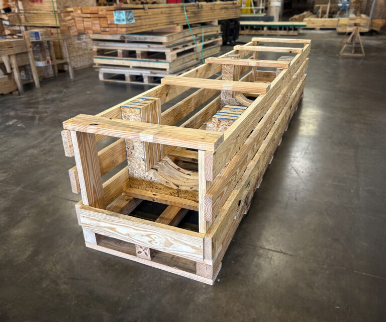 Custom-engineered wooden crate designed to secure long metal gear shafts during transport.