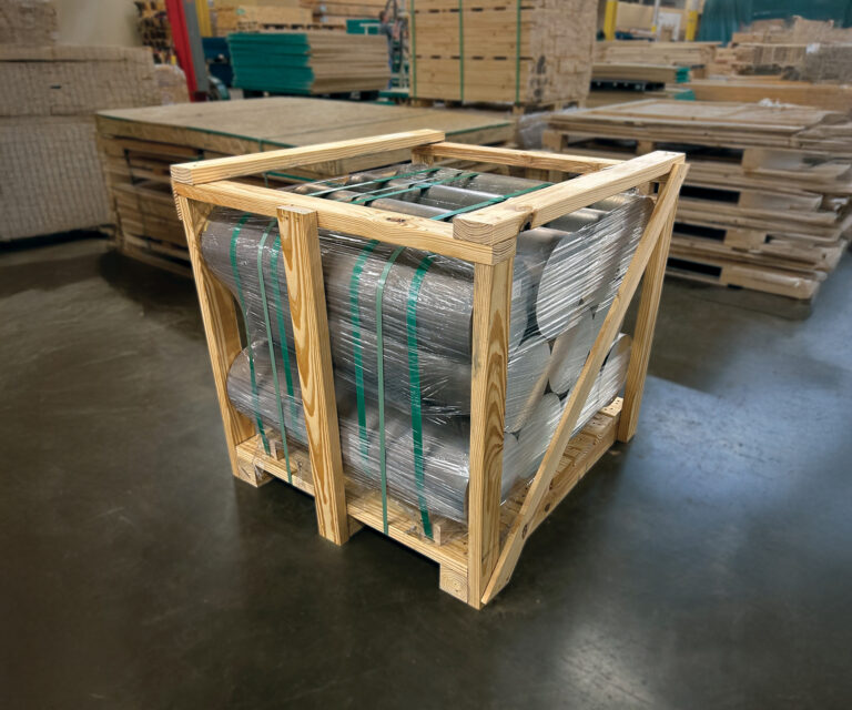 Custom wooden shipping crate holding aluminum billets, secured with green steel straps for export.
